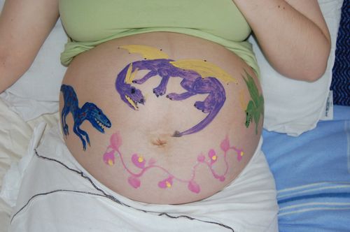 Pregnant belly with painting on it dragons and dinosaurs