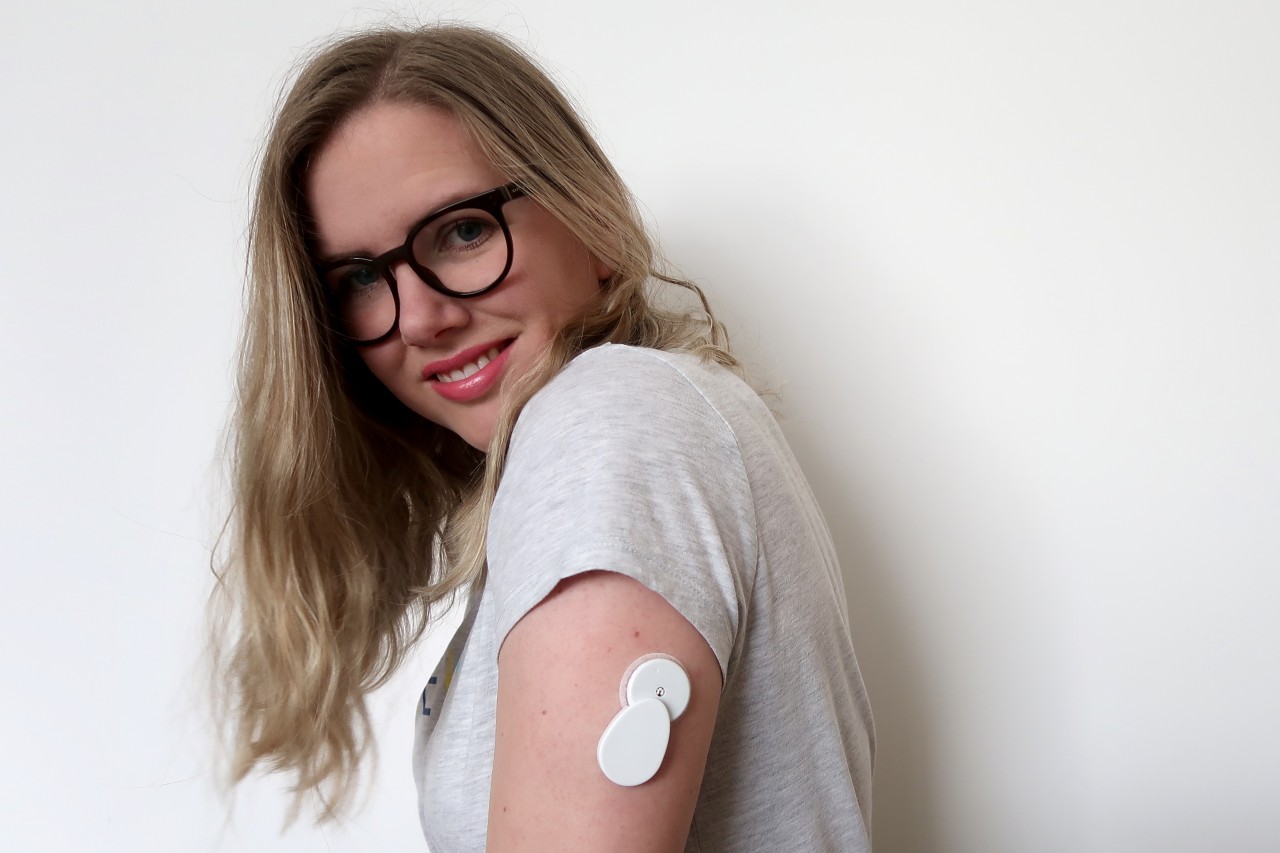 image of woman with long blonde hair and glasses showing insulin pump on her arm